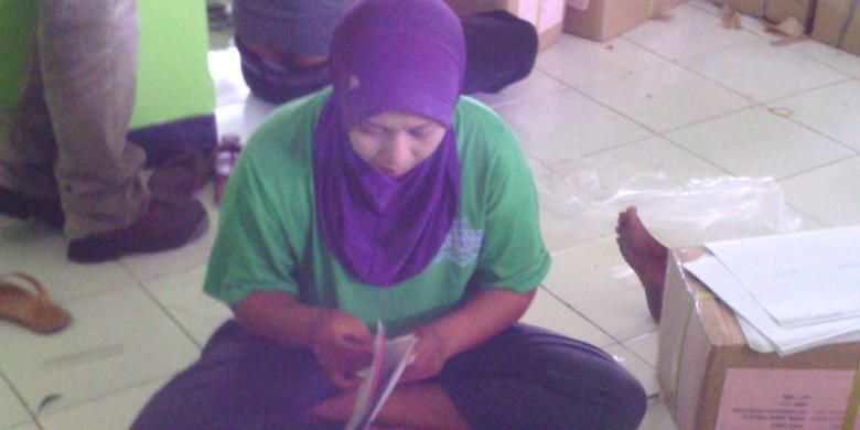 Siti Rohemah, melipat surat suara untuk mencari tambahan penghasilan di luar tugasnya sebagai guru honorer di Pamekasan. 
