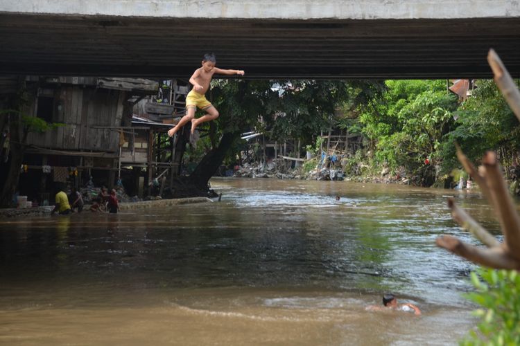 Seorang anak melompat dari titi (jembatan) di Kampung Aur, Kelurahan Aur, Kecamatan Medan Maimun, sesaat setelah banjir di Sungai Deli mulai surut, beberapa waktu lalu. Kota berumur 4 abad di ketinggian 25 MDPL ini tidak seharusnya banjir karena didesain oleh Belanda mengikuti perkembangan zaman.  