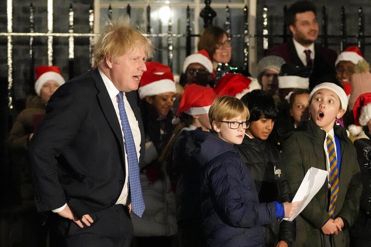 Perdana Menteri Inggris Boris Johnson mendengarkan paduan suara anak-anak bernyanyi selama upacara penyalaan lampu pohon Natal Downing Street di London, Rabu, 1 Desember 2021.
