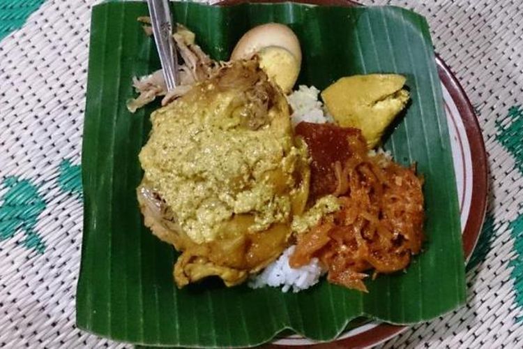 Nasi Ayam disajikan lengkap dengan potongan telur rebus berbumbu, tahu opor, sayur labu manis dengan krecek, dan suwiran ayam, diguyur kuah opor kuning.