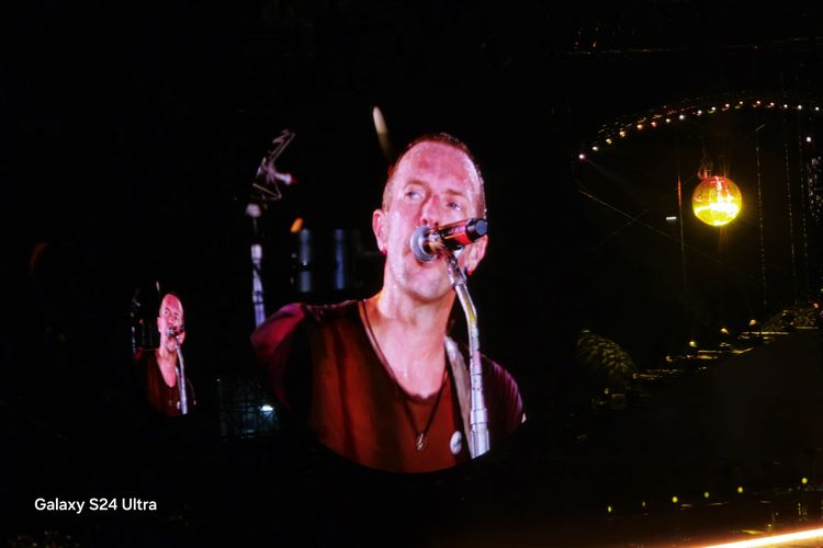 Tampang vokalis Coldplay, Chris Martin yang sedang bernyanyi dalam bidikan Samsung Galaxy S24 Ultra