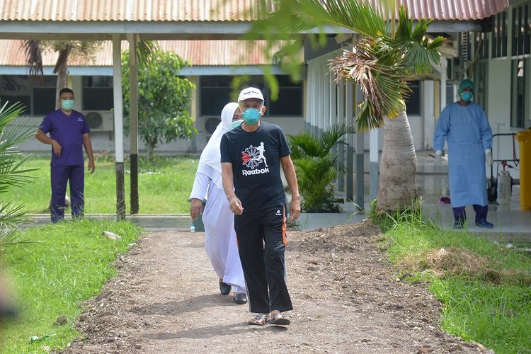 Seorang pasien positif COVID-19  (depan) yang dinyatakan sembuh berjalan menuju ruang tunggu saat proses pemulangan  di Rumah Sakit Zainal Abidin, Banda Aceh, Senin, 13/4/2020). Tim Gugus Tugas Percepatan Penanganan COVID-19 Aceh menyatakan hingga saat ini tercatat sebanyak lima pasien yang sebelumnya dinyatakan positif COVID-19, empat orang  di antaranya sembuh sudah dipulangkan dan seorang pasien lainnya meninggal, sedangkan Pasien Dalam Pengawasan (PDP) sebanyak 60 orang masih dirawat di sejumlah rumah sakit provinsi Aceh. ANTARA FOTO/Ampelsa/hp.