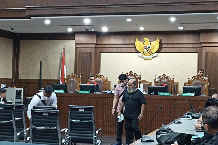Gubernur Papua Lukas Enembe dibantu petugas saat berjalan menuju kursi terdakwa untuk menjalani sidang dugaan suap dan gratifikasi di Pengadilan Tindak Pidana Korupsi, Jakarta Pusat, Senin (10/7/2023).