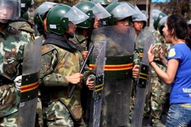 Seorang perempuan Uighur berteriak di depan pasukan paramiliter China di ibu kota wilayah otonomi Uighur, Urumqi pada Juli 2009. Aksi unjuk rasa dan kekerasan kerap terjadi di Xinjiang karena warga Uighur merasa disisihkan oleh etnis Han yang adalah pendatang.

