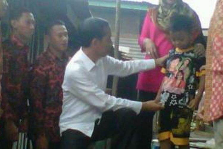 Presdien Jokowi saat mengamati gambar baju Rendi (7) di rumah singgah korban asap di Lorong Keramat Kelurahan 5 Ulu Kecamatan SU I Palembang, Jumat (30/10/2015). 