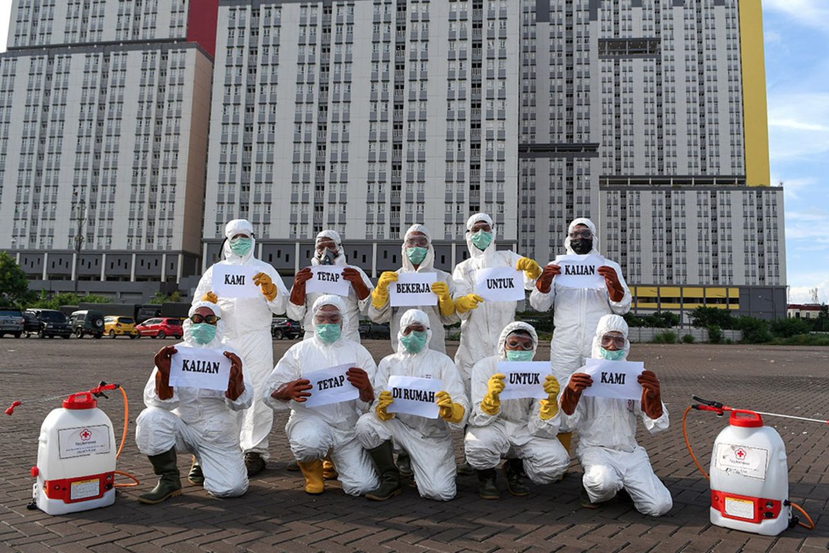 Sejumlah petugas Palang Merah Indonesia (PMI) membawa tulisan Kami Tetap Bekerja Untuk Kalian, Kalian Tetap di Rumah Untuk Kami di Wisma Atlet, Kemayoran, Jakarta, Sabtu (21/3/2020). Kegiatan tersebut sebagai imbauan bagi masyarakat sebagai upaya pencegahan penyebaran virus COVID-19.