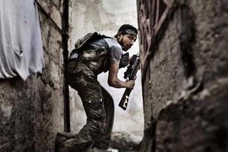 Seorang anggota pasukan pemberontak Suriah tengah mencari posisi di sela-sela bangunan di kota Aleppo. Pasukan pemberontak FSA mengancam akan membalas serangan Hezbollah yang menembaki posisi mereka di Provinsi Homs.