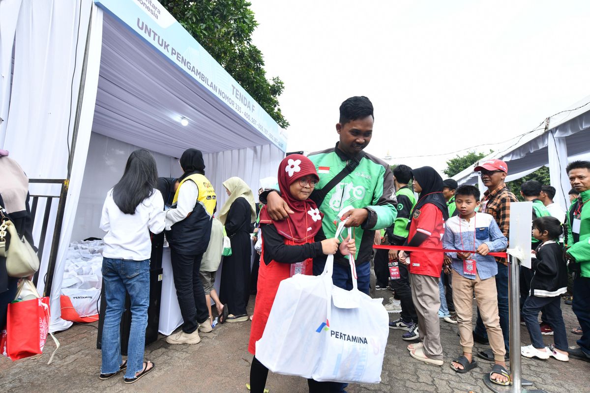 Seorang pengemudi ojek online mengantar anaknya mengambil paket perlengkapan sekolah dari Pertamina dalam program SESAMA di Jakarta, Minggu (13/7/2025). Program ini ditujukan untuk mendukung pendidikan anak-anak pengemudi ojek di Jabodetabek.