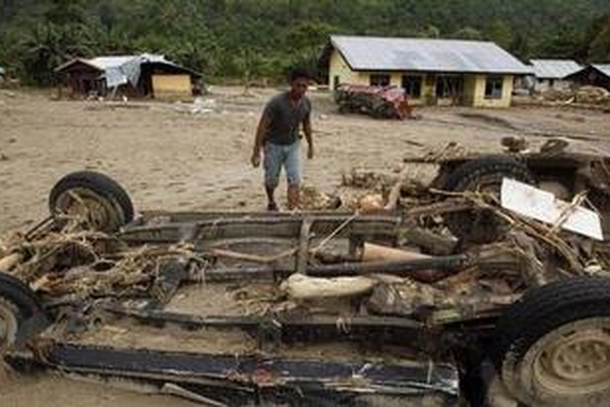 Seorang warga mengamati bangkai mobil yang terendam lumpur pascabanjir bandang di Wasior, Teluk Wondama, Papua, Senin (4/10/2010)