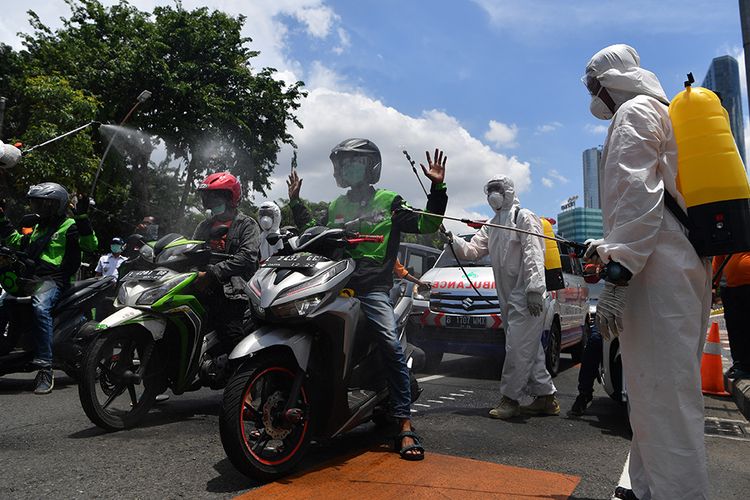 Petugas Badan Penanggulangan Bencana Daerah (BPBD) Jatim menyemprotkan cairan disinfektan ke pengendara ojek daring di Surabaya, Jawa Timur, Minggu (22/3/2020).Penyemprotan yang dilakukan ke sejumlah pengnedara motor dan angkutan publik tersebut untuk mencegah penyebaran Virus Corona (COVID-19).