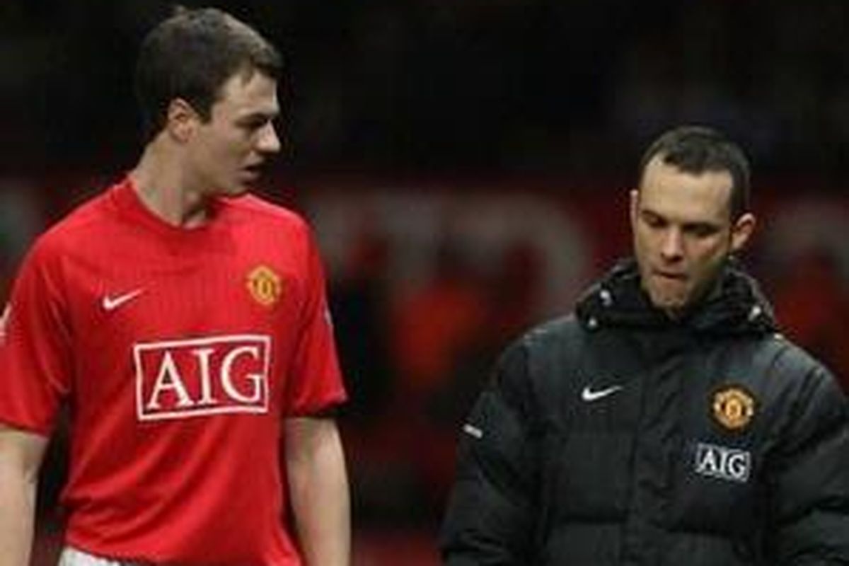 Jonny Evans (kiri) meninggalkan lapangan pertandingan karena cedera. Dia diragukan tampil di leg pertama 16 besar Liga Champions.