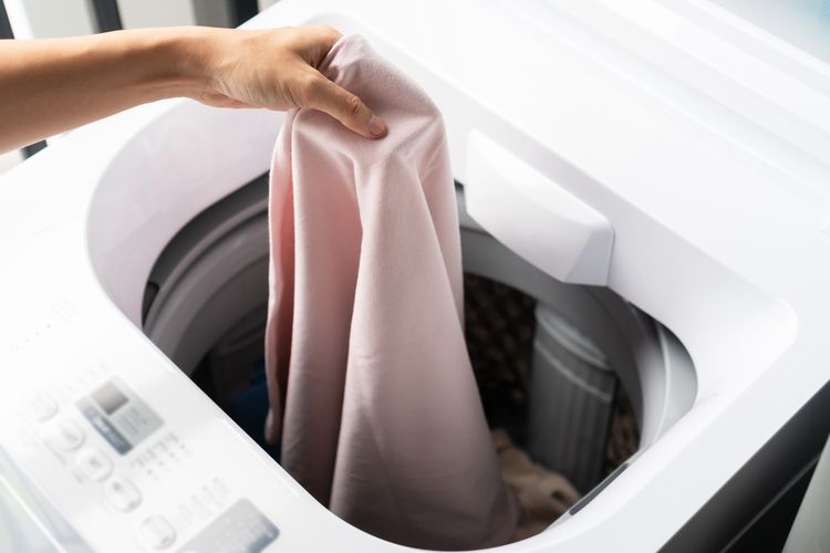 Ilustrasi mencuci pakaian menggunakan mesin cuci.
