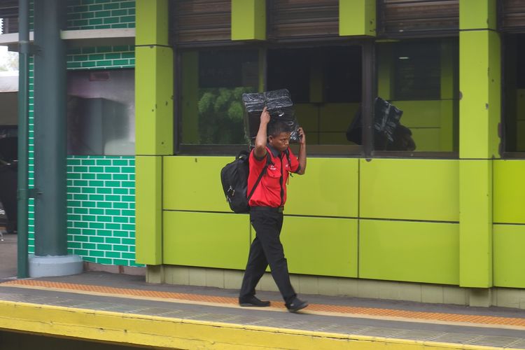 Porter Stasiun Gambir tampak membawa barang penumpang yang menggunakan jasanya. Meski dibayar sukarela, porter Stasiun Gambir biasanya diberi harga atas jasanya Rp 25.000 hingga Rp 35.000.