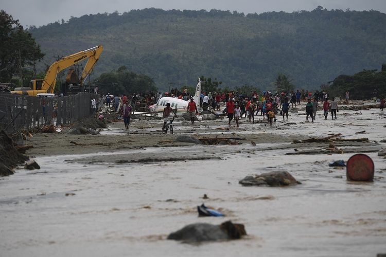 Warga mengamati sebuah pesawat yang terseret banjir bandang di Sentani, Jaya Pura, Papua, Senin (18/3/2019). Akibat banjir bandang yang melanda Sentani sejak Sabtu (16/3) lalu, sedikitnya empat ribu warga mengungsi di sejumlah posko pengungsian. ANTARA FOTO/Zabur Karuru/foc.