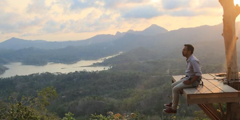 Pengunjung menjajal sensasi berfoto di menara pandang di atas pohon (spot foto), Kamis (8/10/2015). Terlihat dalam latar foto itu Waduk Sermo, perbukitan Menoreh, serta Gunung Susukan dan Gunung Ijo. 