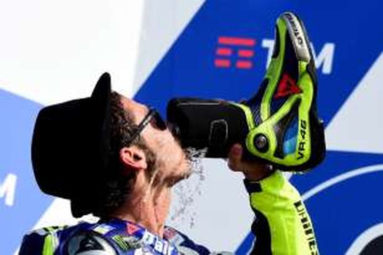 Pebalao Movistar Yamaha asal Italia, Valentino Rossi, meminum sampanye dari sepatunya untuk merayakan hasil finis di urutan kedua pada balapan GP San Marino di Sirkuit Misano, Minggu (11/9/2016).