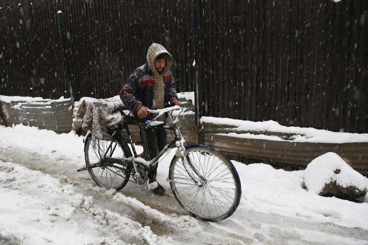 Seorang pria menuntun sepedanya melewati hamparan salju di Srinagar, Kashmir, India, 7 November 2019.