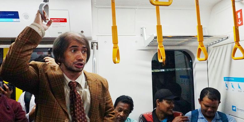 Artis peran Reza Rahadian memakai kostum karakter Bossman di film My Stupid Boss 2 diabadikan saat menyapa penumpang MRT rute Bundaran HI-Lebak Bulus, Jumat (29/3/2019).