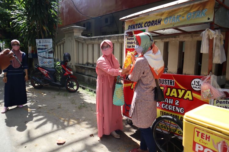 BERBAGI—Rima Darma, istri anggota Brimobda Polda Jatim Kompi II Den C Madiun membagikan minyak goreng kemasan gratis bagi pedagang gorengan di Kota Ponorogo, Jawa Timur, Selasa (25/1/2022).