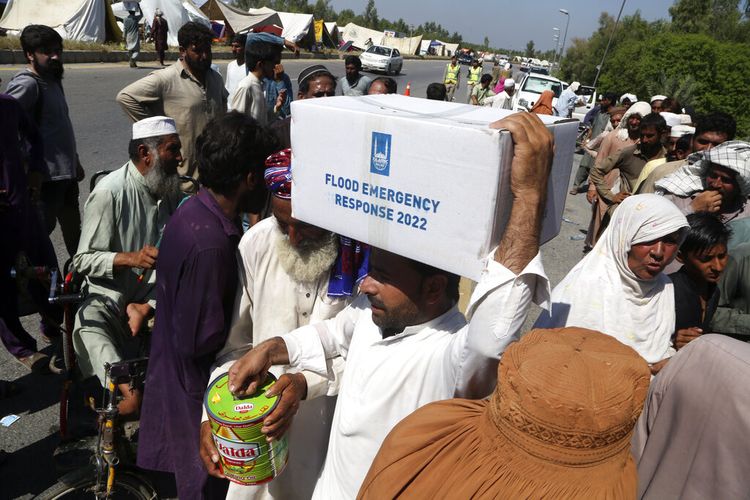 Keluarga pengungsi berbaris untuk menerima makanan setelah meninggalkan rumah mereka yang terkena banjir untuk berlindung di pinggir jalan, di Charsadda, Pakistan, Senin, 29 Agustus 2022. 