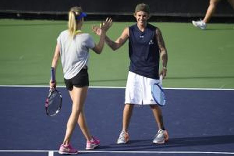 Petenis Kanada, Eugenie Bouchard (kiri), melakukan tos dengan bintang pop Justin Bieber dalam pertandingan Annual Desert Smash di La Quinta Resort and Club, California, Selasa (10/3/2015).