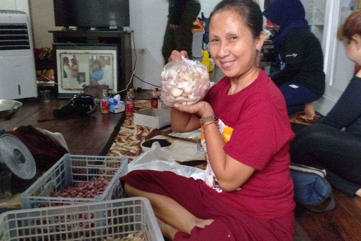 Suryani (Acung) sedang membungkus bawang yang dia jual, Kamis (2/7/2020)