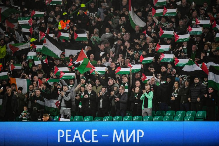 Pendukung memegang bendera Palestina saat mereka bersorak sebelum dimulainya pertandingan sepak bola grup E Liga Champions UEFA antara Celtic dan Atletico Madrid di stadion Celtic Park, Glasgow, Skotlandia, 25 October 2023. (Photo by ANDY BUCHANAN / AFP)