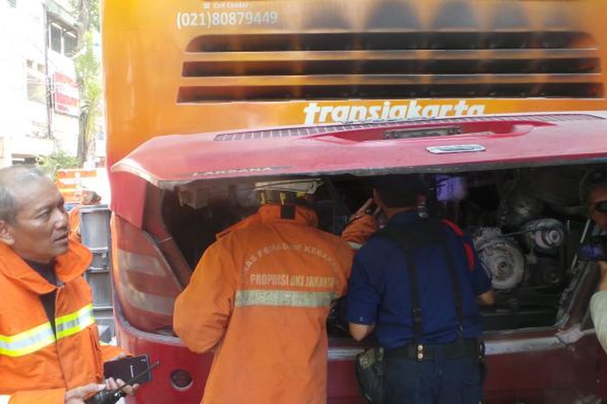 Beberapa petugas pemadam kebakaran mengecek bagian mesin bus transjakarta yang terbakar di Halte Stasiun Jatinegara 2. Dari mesin belakang bus ini diduga awal terjadinya kebakaran. Sabtu (18/7/2015).