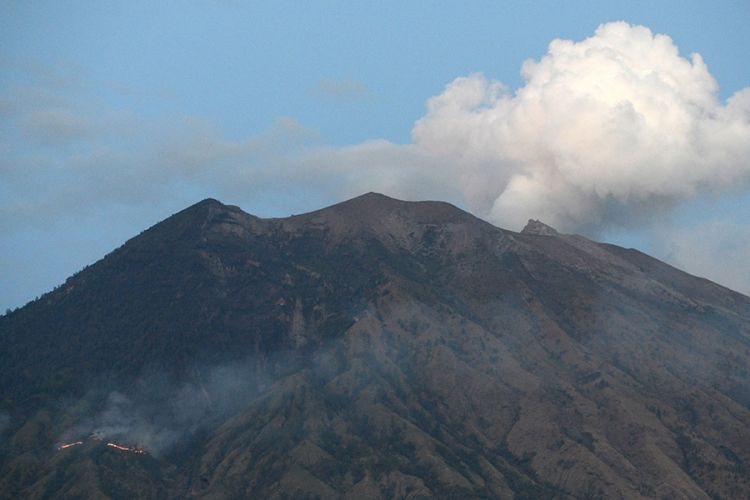 Asap dari api yang membakar hutan lereng Gunung Agung setelah terjadinya lontaran batu pijar dari kawah, terlihat dari Desa Tulamben, Karangasem, Bali, Selasa (3/7/2018). Pusat Vulkanologi dan Mitigasi Bencana Geologi mencatat terjadinya erupsi Gunung Agung dengan tinggi kolom abu mencapai 2.000 meter yang disertai lontaran batu pijar sejauh dua kilometer.