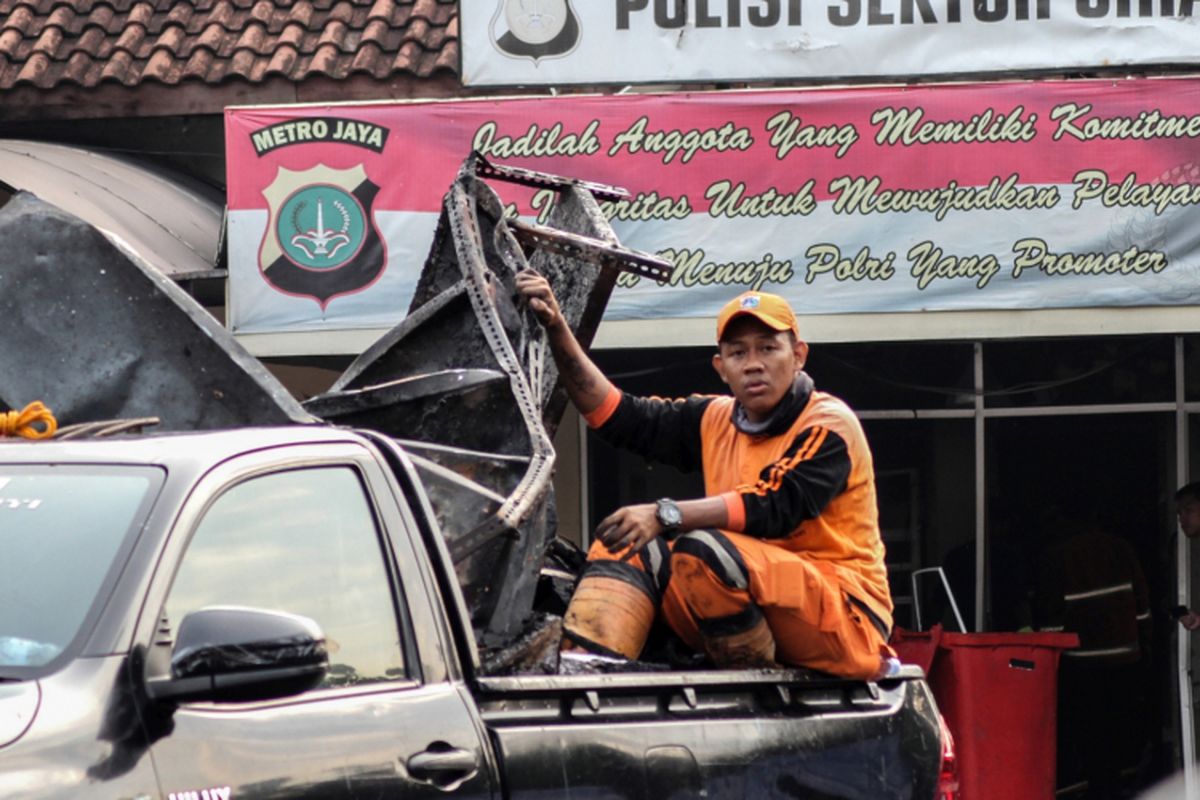 Petugas kebersihan mengangkut barang sisa perusakan dan pembakaran di Polsek Ciracas, Jakarta, Rabu (12/12/2018). Perusakakan dan pembakaran Polsek Ciracas yang dilakukan ratusan orang itu  terjadi pada Rabu dini hari (12/12/2018), yang dipicu ketidakpuasan atas penanganan kasus pemukulan seorang anggota TNI.