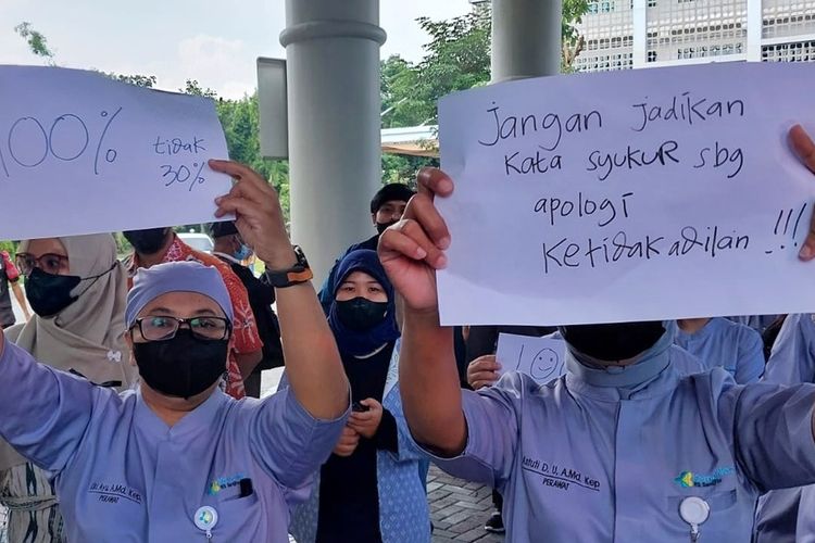 Para pegawai RSUP Dr Sardjito Yogyakarta saat berjalan sembari membawa poster. Para pegawai ini memprotes diberikanya THR 30 persen dari besaran insentif.