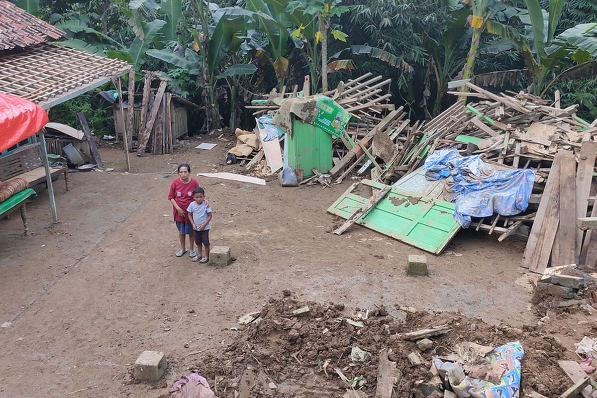 Jumini (65) di tengah puing rumah yang han ur akibat tanah longsor di Pedukuhan Plampang II, Kalurahan Kalirejo, Kapanewon Kokap, Kabupaten Kulon Progo, Daerah Istimewa Yogyakarta, Jumat (1/6/2022) malam.