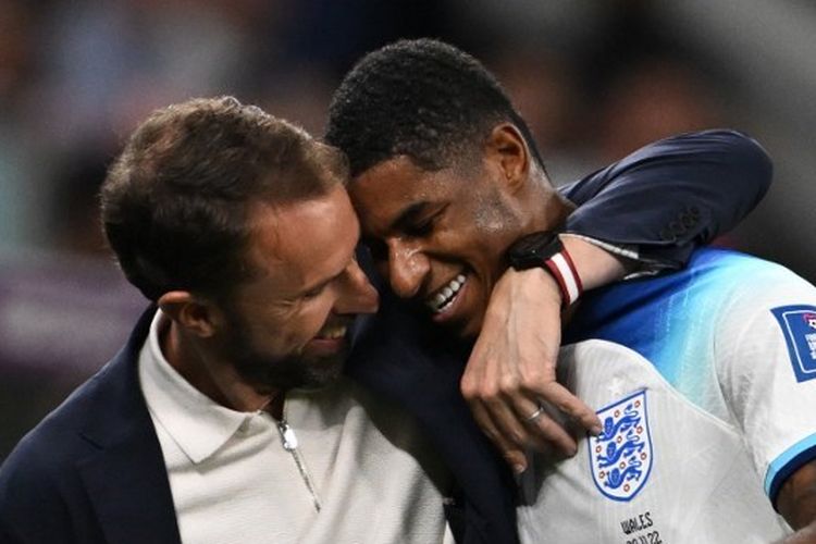 Pelatih timnas Inggris, Gareth Southgate (kiri), memberi ucapan selamat kepada Marcus Rashford usai laga terakhir Grup B Piala Dunia 2022 kontra Wales di Stadion Ahmad bin Ali, Al Rayyan, Qatar, pada Selasa (29/11/2022) malam waktu setempat. Inggris lolos ke 16 besar sebagai juara Grup B berkat kemenangan 3-0 atas Wales. (Photo by Paul ELLIS / AFP)