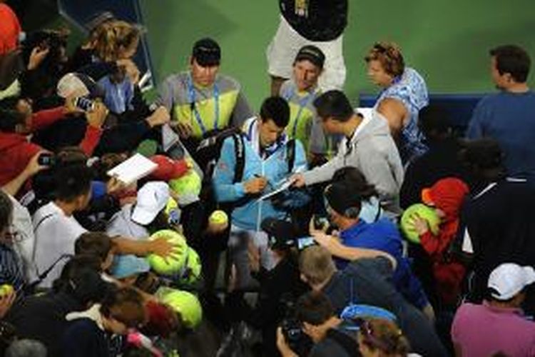 Petenis Serbia, Novak Djokovic (tengah), memberikan tanda tangan kepada para penonton setelah memenangi laga babak kedua Western & Southern Open melawan petenis Perancis, Gilles Simon, di Cincinnati, Selasa (12/8/2014). Djokovic menang 6-3, 4-6, 6-4.