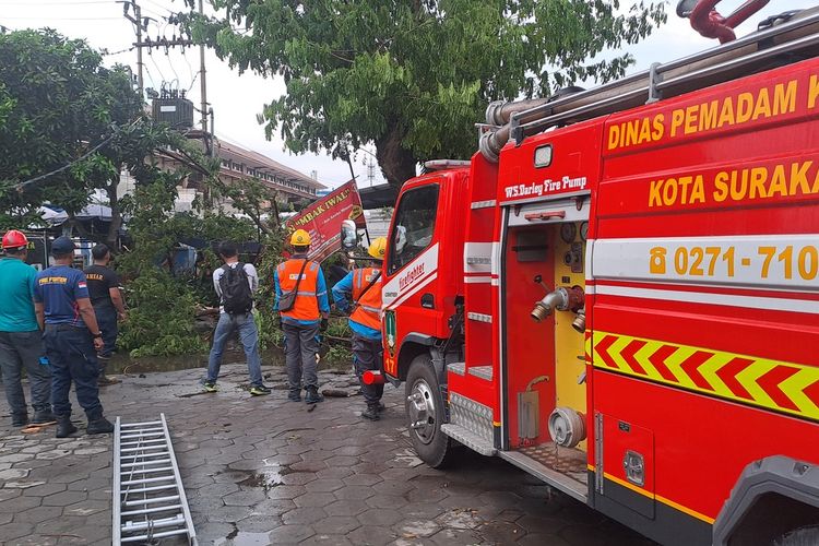 Proses evakuasi ranting pohon tumbang menimpa warung makan dan sepada motor hujan deras disertai angin kencang, telah berlangsung di area Taman Parkir, Kompleks Masjid Agung Kota Solo, Jawa Tengah (Jateng), Jumat (31/10/2025).