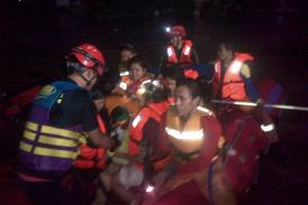 Petugas mengevakuasi sepasang suami istri dan bayi mereka yang baru berumur satu bulan di lokasi banjir di Kampung Pulo, Kampung Melayu, Jakarta Selatan, Minggu (12/1/2014) malam.