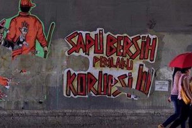 Warga melintas di depan poster berisi kritikan terhadap perilaku korupsi di kolong jalan kereta api Manggarai, Jakarta Selatan, Minggu (16/12/2012). Kritikan terhadap pelaku koruptor terus disuarakan oleh aktivis untuk mendorong tindakan lebih tegas dalam pemberantasan korupsi dan penegakan hukum lainnya.
