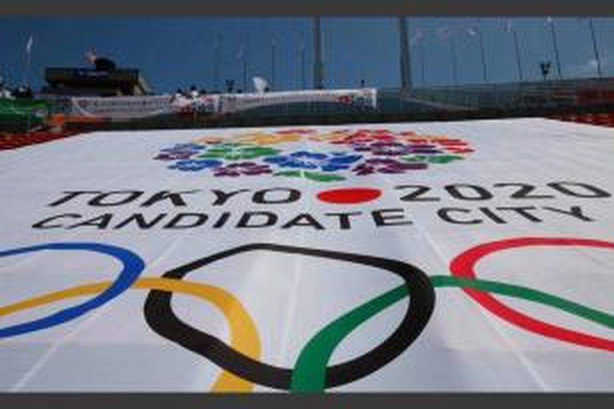 Warga berdiri melihat api yang menyala di kaldron Olimpiade, yang digunakan dalam Olimpiade Tokyo 1964, di dekat banner bertuliskan logo resmi Tokyo untuk Olimpiade 2020 di Stadion Nasional, 1 September 2013.