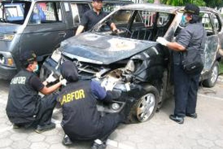 Tim Labfor Cabang Semarang memeriksa mobil Toyota Avanza milik FPI yang dibakar massa di Kendal, Jawa Tengah, Senin (22/7/2013).