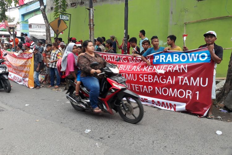 Massa pendukung Jokowi membentangkan spanduk saat menyambut Prabowo Subianto di Surabaya, Selasa (19/2/2019)