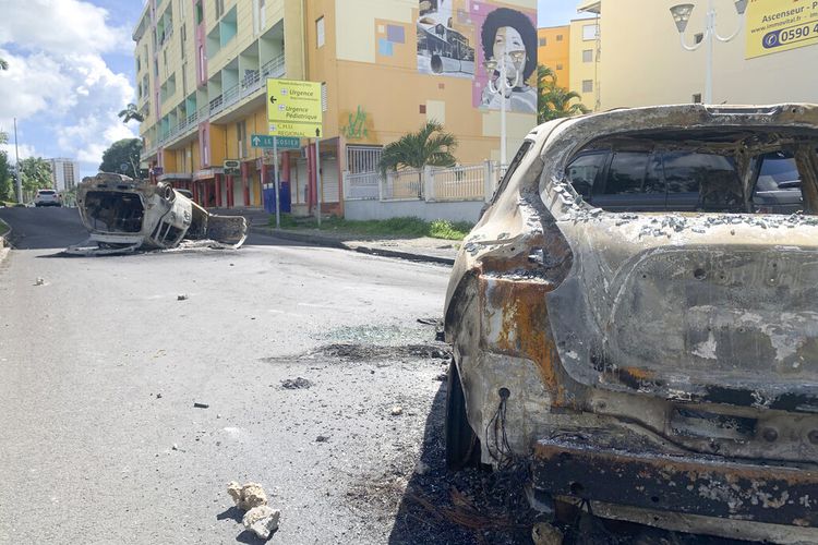 Mobil hangus terlihat di jalan Le Gosier, pulau Guadeloupe, Minggu, 21 November 2021, setelah protes atas pembatasan COVID-19 meletus menjadi kerusuhan dan penjarahan selama tiga hari berturut-turut. 