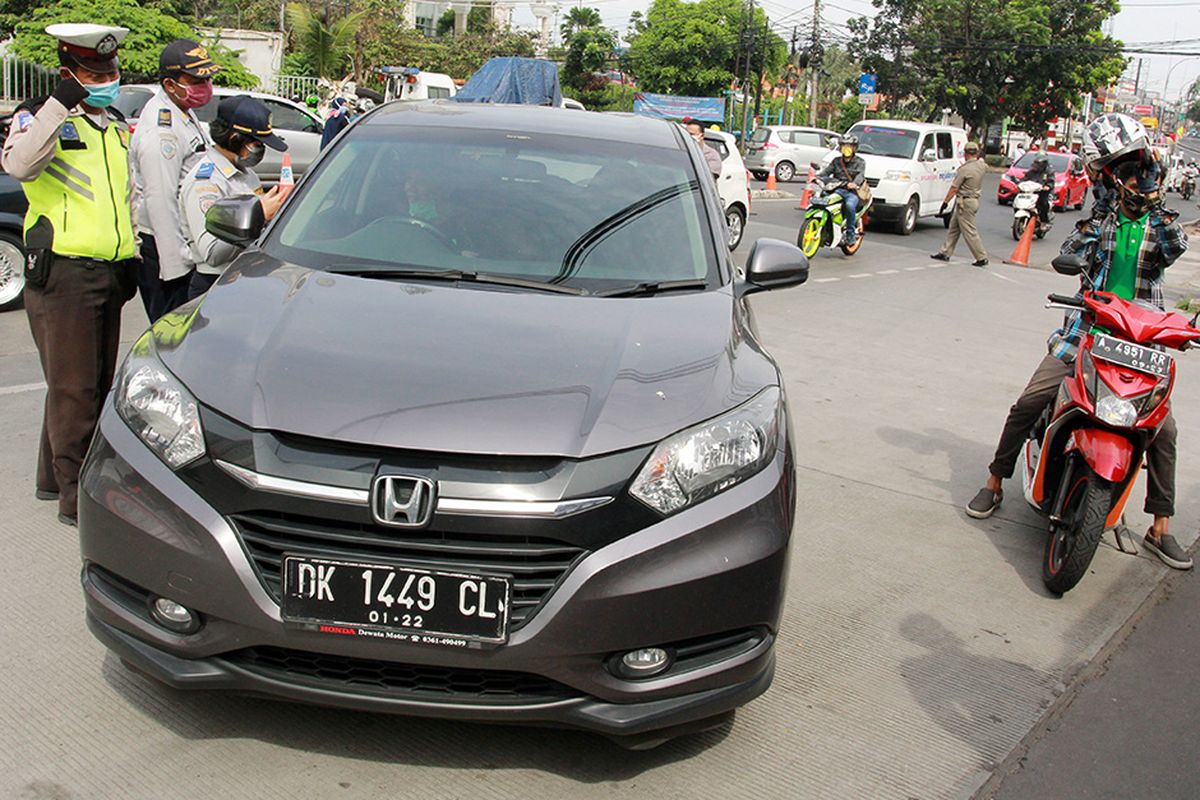 Petugas Kepolisian dan Dishub Jakarta memeriksa surat kelengkapan kendaraan dan juga surat izin keluar masuk (SIKM) Jakarta saat razia plat nomor kendaraan luar Jakarta di Jalan Ciledug Raya, Jakarta, Rabu (27/5/2020). Pengendara yang tidak memiliki SIKM Jakarta kemudian diputar balik agar tidak memasuki wilayah Ibu Kota.