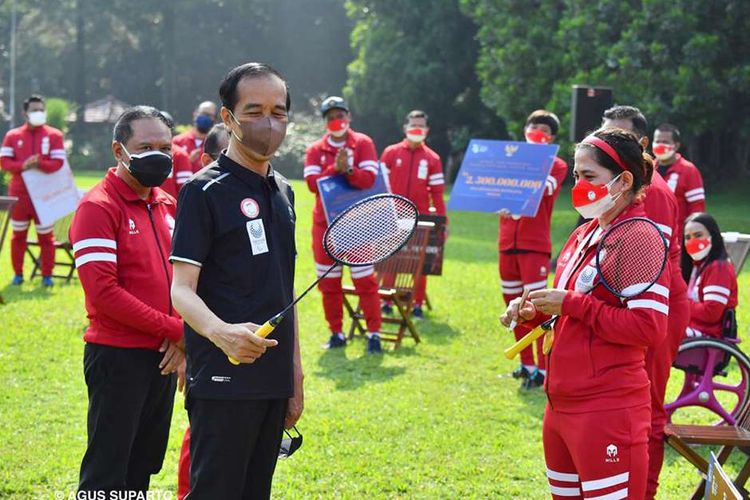 Presiden Joko Widodo menerima kenang-kenangan raket yang dipakai atlet bulu tangkis Leani Ratri Oktila saat berjuang meraih medali emas ajang Paralimpiade Tokyo 2020, di halaman belakang Istana Kepresidenan Bogor, Jawa Barat, Jumat (17/9/2021). Presiden Joko Widodo menerima kontingan Paralimpiade Tokyo 2020 di Istana Kepresidenan Bogor sekaligus menyampaikan apresiasi dan memberikan bonus kepada atlet dan pelatih yang berlaga di ajang olahraga tersebut.