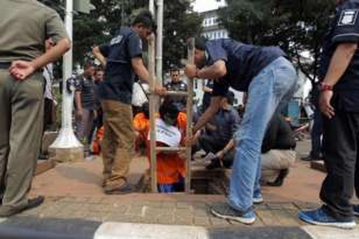 Salah satu tersangka menjalani rekonstruksi pencurian kabel di Jalan Medan Merdeka Selatan, Selasa (15/3/2016). Sebanyak enam tersangka melakukan lebih dari 10 adegan saat menjalani rekonstruksi.