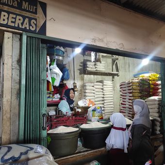 Muryati (58) pedagang beras di pasar tradisional Bintoro Demak saat melayani pelanggan, Senin (4/3/2024). (KOMPAS.COM/NUR ZAIDI)