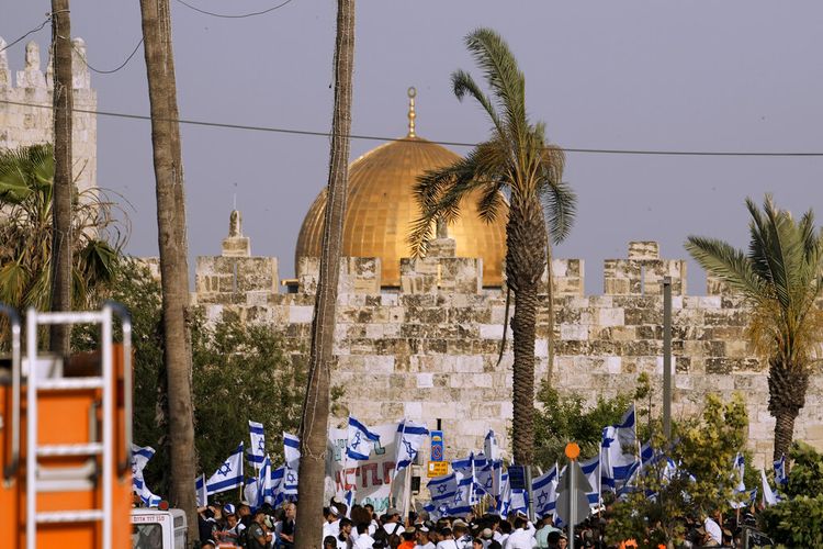 Warga Israel mengibarkan bendera nasional di depan Gerbang Damaskus di luar Kota Tua Yerusalem untuk menandai Hari Yerusalem, hari libur Israel yang merayakan penaklukan terhaadap Kota Tua selama perang Timur Tengah 1967, Minggu (29/5/2022).