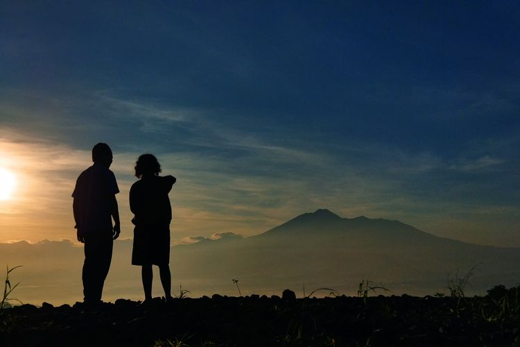 Dua orang wisatawan tengah menikmati pemandangan Gunung Gede Pangrango saat momen golden sunrise yang dilihat dari Desa Pasirjaya, Kecamatan Cigombong, Kabupaten Bogor pada Kamis (27/5/2021). Pendakian Gunung Gede Pangrango tutup saat 17 Agustus 2022.