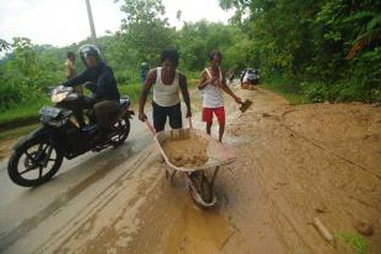 Lumpur akibat tanah longsor menutupi separuh jalan di Desa Pamoroh, Kecamatan Kadur Pamekasan. Lumpur harus diberishkan agar tak menutupi seluruh badan jalan. 