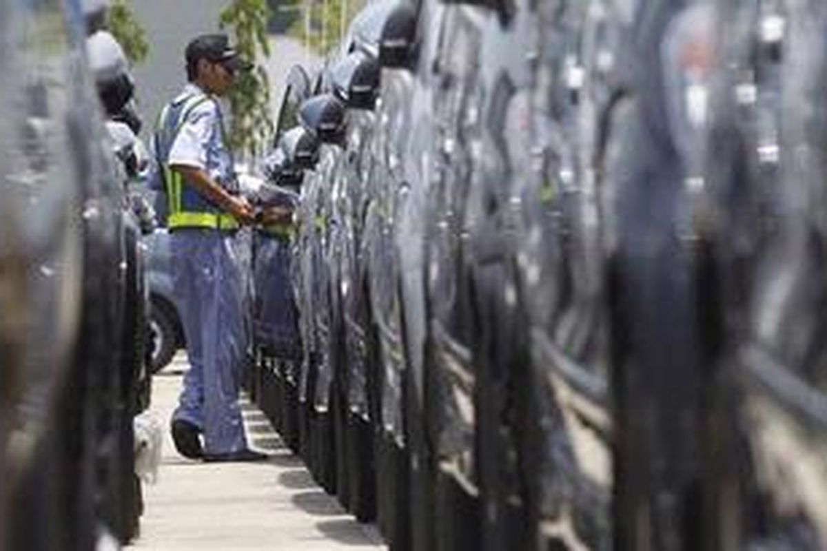 A worker checks new cars before loading them into the ship for delivery to other provinces at the Tanjung Priok port in Jakarta October 22, 2010. Indonesia is selling cars faster than it is building roads, increasing gridlock in cities and doing its efforts to attract foreign direct investment no favours.