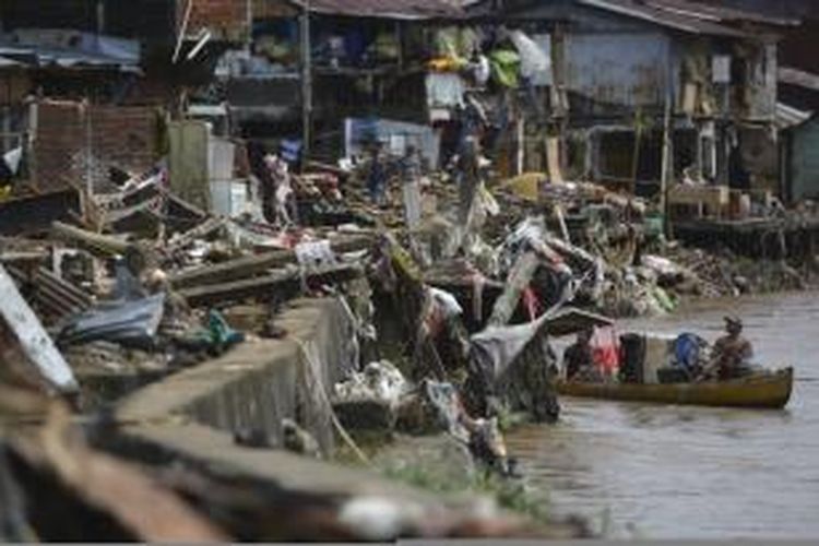 Menggunakan perahu, pemulung mengumpulkan barang yang sudah tidak terpakai namun masih memiliki nilai ekonomi di puing-puing rumah yang hancur akibat banjir bandang di pinggir Sungai Tondano, Karame, Kecamatan Singkil, Manado, Sulawesi Utara, Jumat (17/1). Kompas/Heru Sri Kumoro (KUM)
